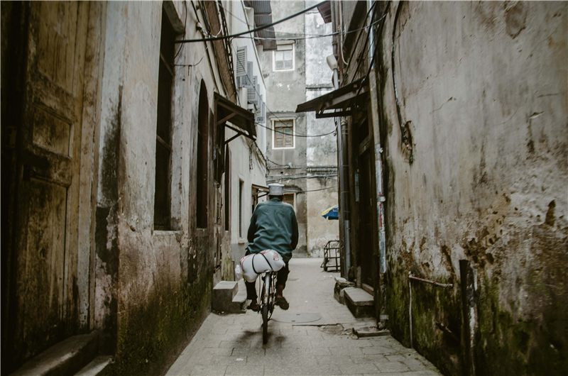 Cyclist riding through a narrow stone alley.