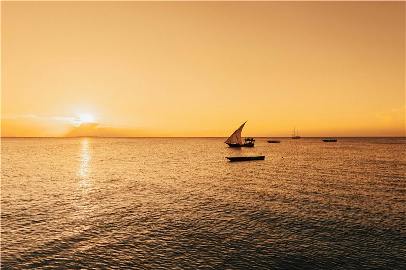 Dhow sailing on calm Zanzibar waters at sunset
