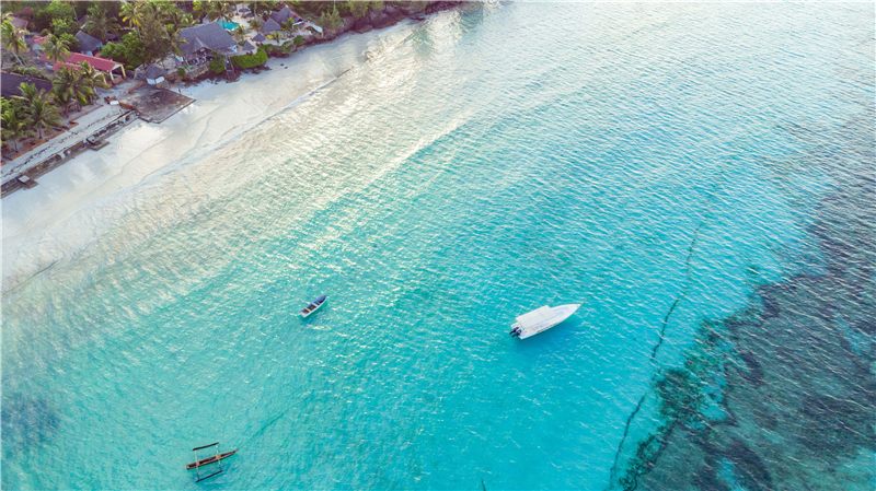 Aerial view of a small boat in shallow blue water.