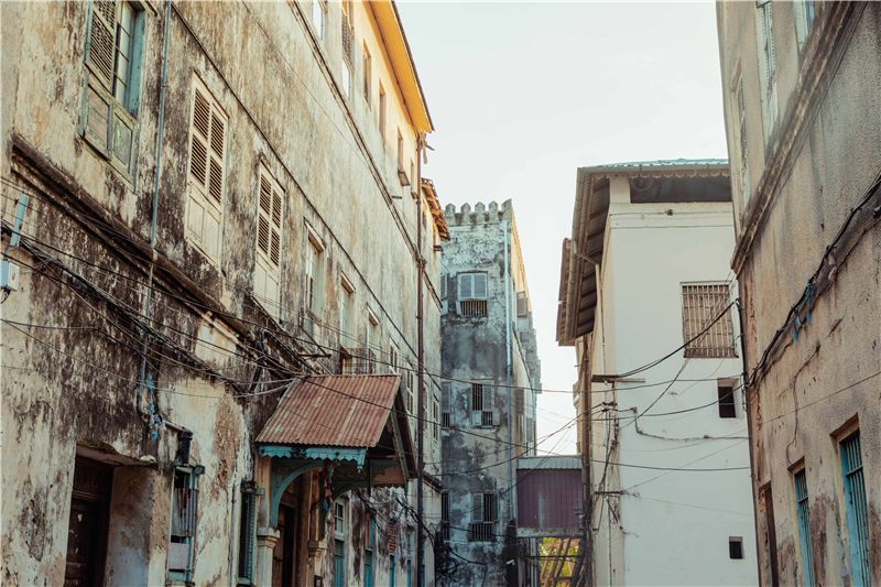 Narrow street between weathered stone buildings.